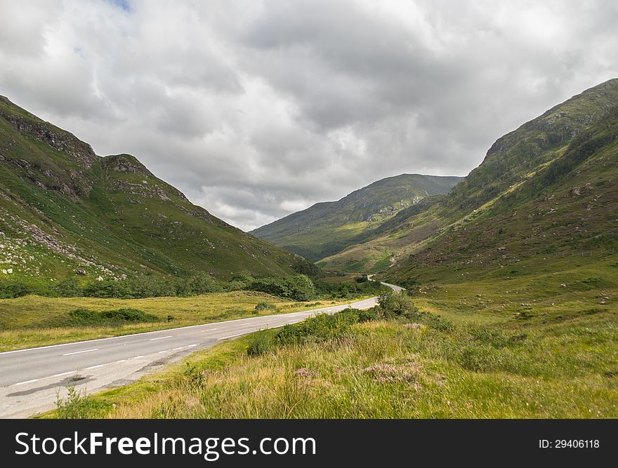 Empty road in the middle of scottish highland during a summer day with cloudy sky. Empty road in the middle of scottish highland during a summer day with cloudy sky