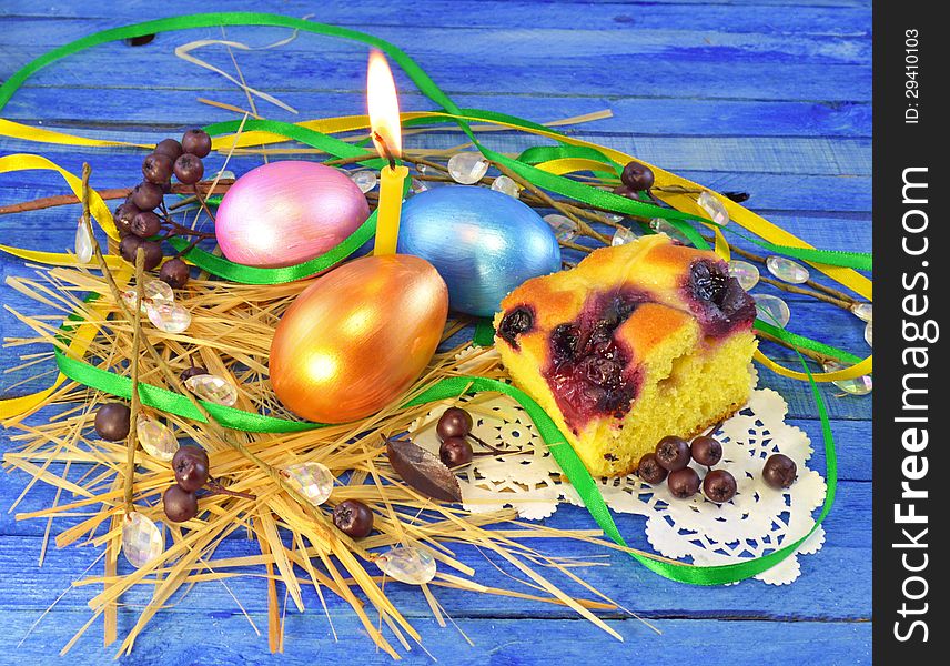 Three easter eggs with candle and cake on the blue background. Three easter eggs with candle and cake on the blue background