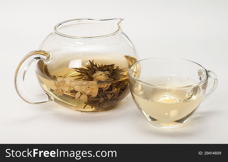 Jasmine tea in a glass teapot on a white background . Jasmine tea in a glass teapot on a white background .