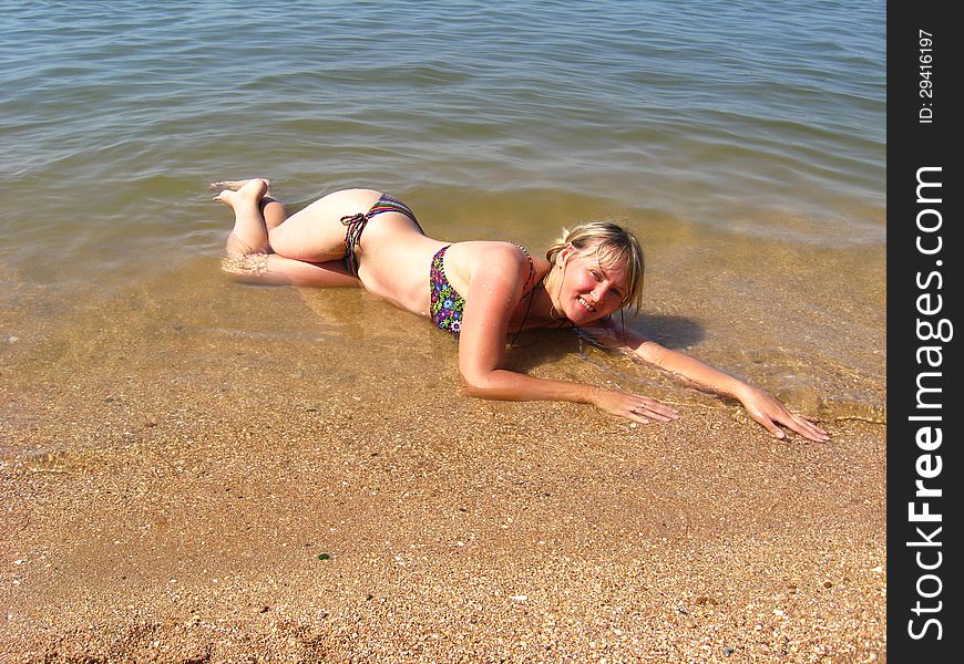 Sympathetic girl laying on sand at the sea. Sympathetic girl laying on sand at the sea