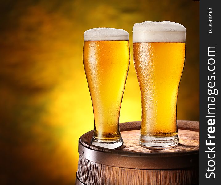 Two Glasses Of Beer On A Wooden Barrel.