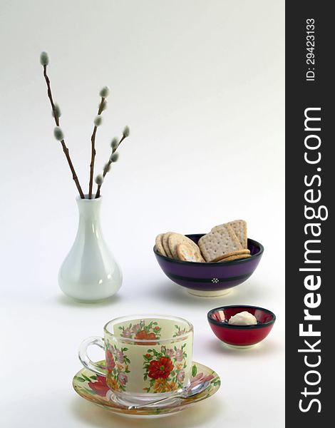 Tea cup and saucer, bowl with cookies, candy and white vase with willow sprigs. Tea cup and saucer, bowl with cookies, candy and white vase with willow sprigs