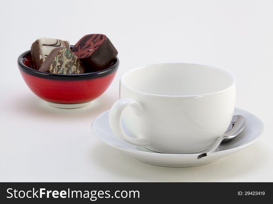 Cup with saucer and spoon and small bowl of chocolates. Cup with saucer and spoon and small bowl of chocolates