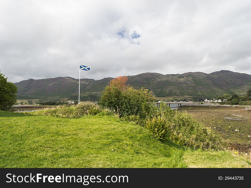 The Saltire flag above near Eilean Donan Castle, Dornie Village, Skye Island Scotland. The Saltire flag above near Eilean Donan Castle, Dornie Village, Skye Island Scotland