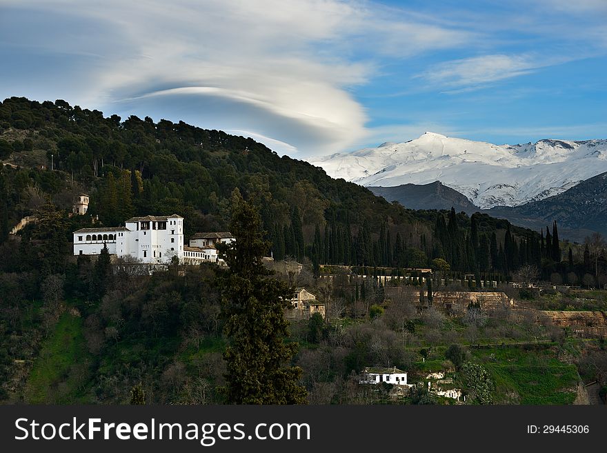 Aerial view of Alhambra and snowing Sierra Nevada mountains under a lenticular cloud