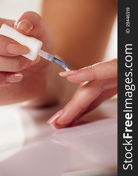 Close up of woman applying neutral nail polish