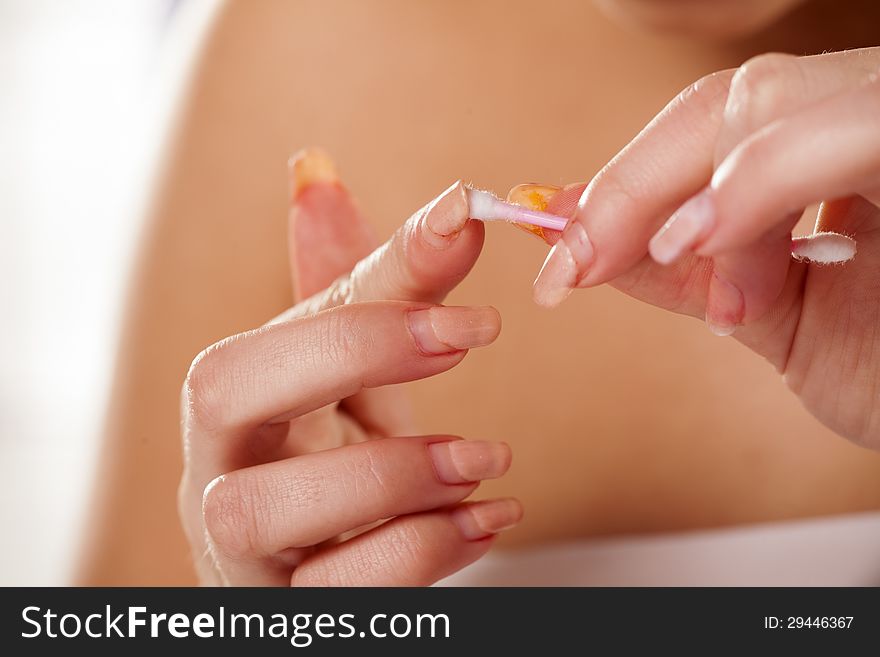 Girl cleans her nails with a cotton swab with focus on foreground. Girl cleans her nails with a cotton swab with focus on foreground