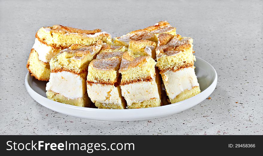 Sponge cakes with white cream and cinnamon on gray table. Sponge cakes with white cream and cinnamon on gray table