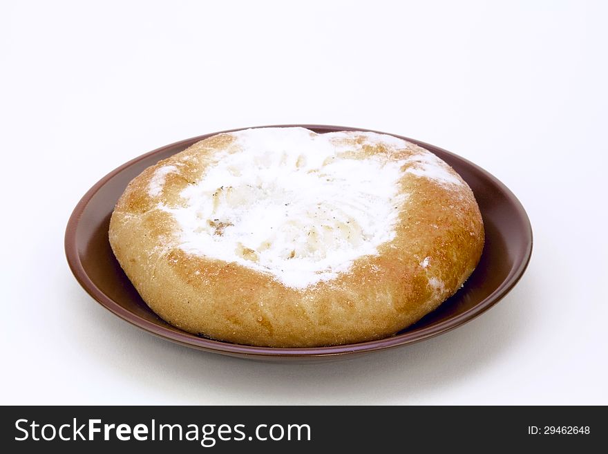 Cheese cake on a brown saucer, dusted with icing sugar