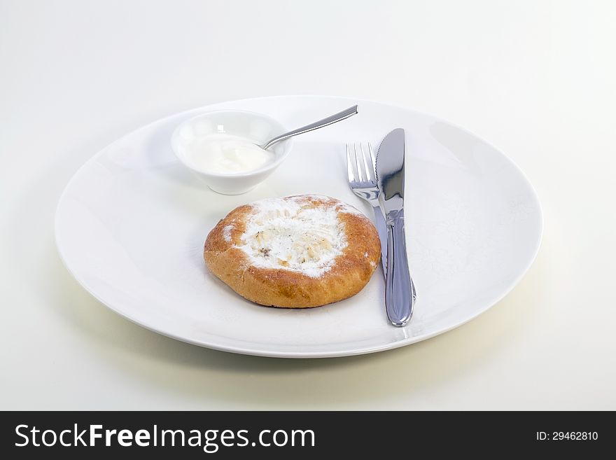 Cheese cake with sour cream on a white plate, knife and fork
