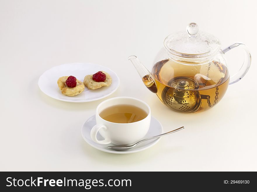 A cup of tea, candied fruits on a saucer and teapot with strainer. A cup of tea, candied fruits on a saucer and teapot with strainer