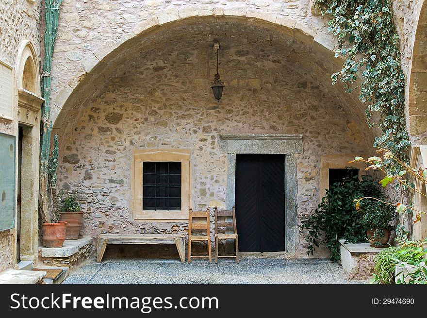 Courtyard of a convent with a bench and chairs on Crete, Greece