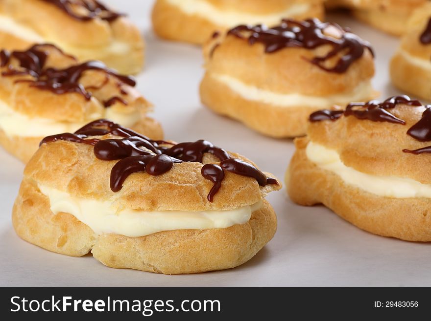 Cream filled eclair with chocolate icing on baking sheet. Cream filled eclair with chocolate icing on baking sheet