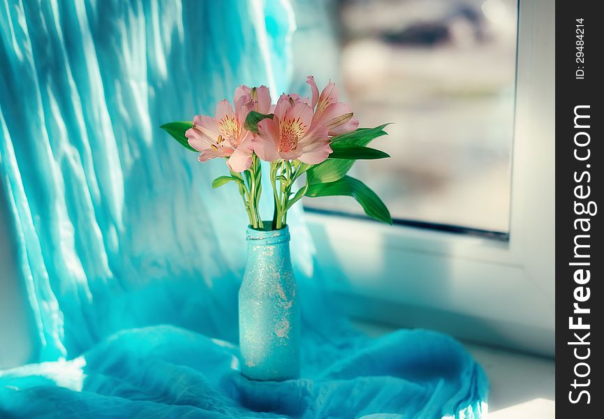 On a blue background and a blue vase delicate ornamental flowers. On a blue background and a blue vase delicate ornamental flowers