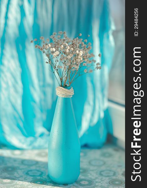 On a blue background and a blue vase delicate white flowers. On a blue background and a blue vase delicate white flowers