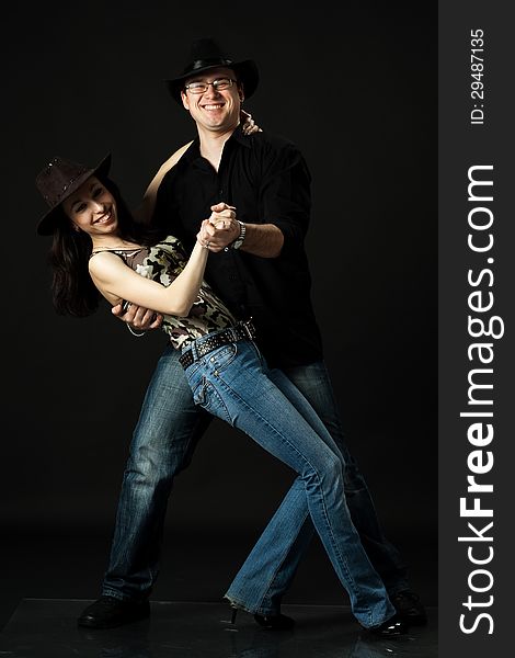 Handsome young couple dancing in studio on black background