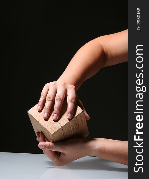 Hands holding a wooden cube infront of the black background. Hands holding a wooden cube infront of the black background