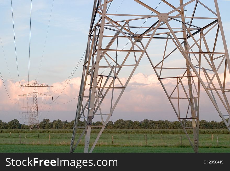 Power lines in a meadow against a moody sky. Power lines in a meadow against a moody sky