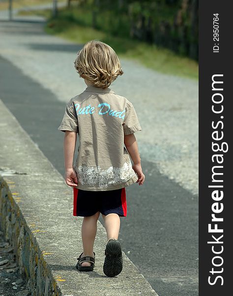 A little boy walking along a wall in north wales. A little boy walking along a wall in north wales.