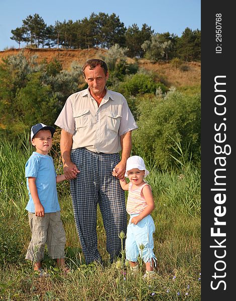Grandfather with grandchildren staying on a grass