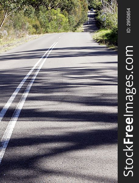 Asphalt Country Road Winding Down A Hill, Sunny Day, Shadows On Street