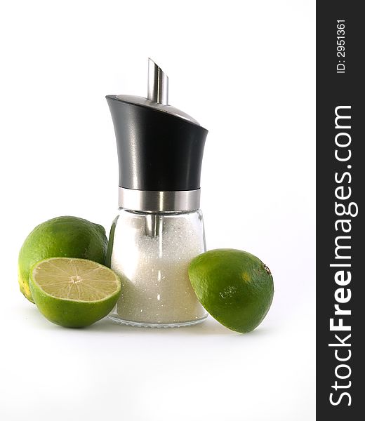 Two halves of green lime and sugar dispenser liyng on the white background