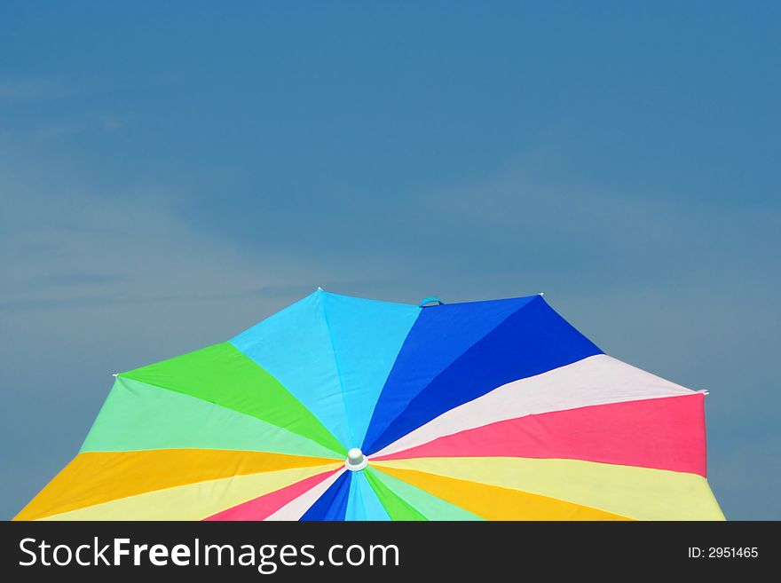 A Colorful Beach Umbrella is Framed against a Blue Sky. A Colorful Beach Umbrella is Framed against a Blue Sky.