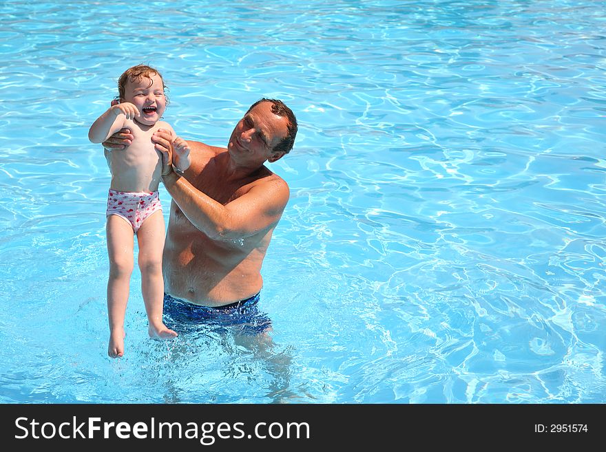 Grandfather standing in pool holds granddaughter. Grandfather standing in pool holds granddaughter