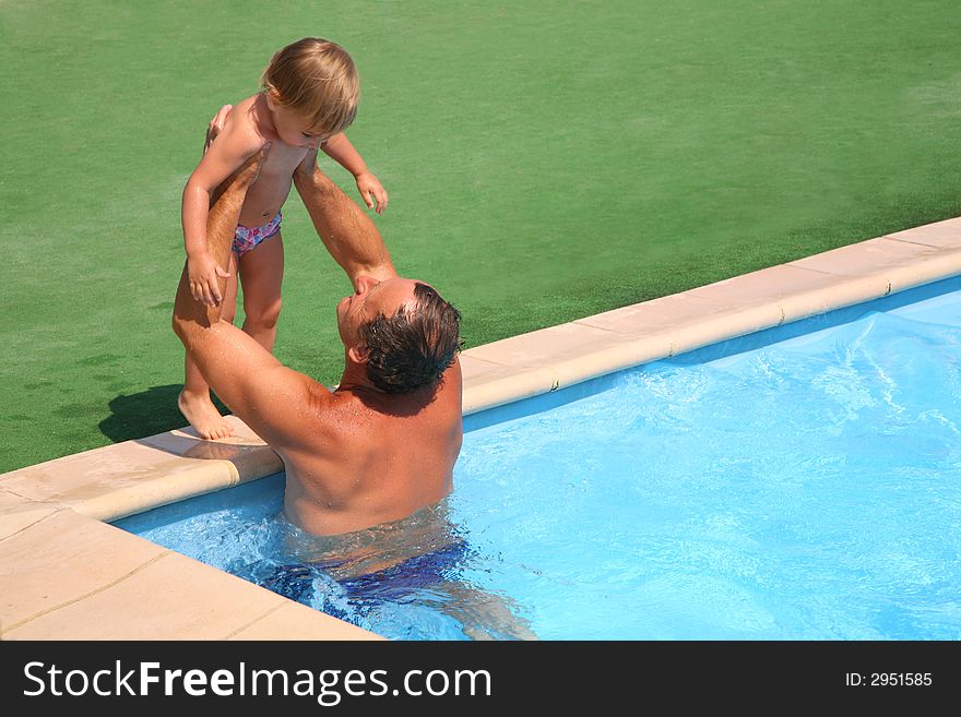Grandfather standing in pool holds on hands granddaughter. Grandfather standing in pool holds on hands granddaughter