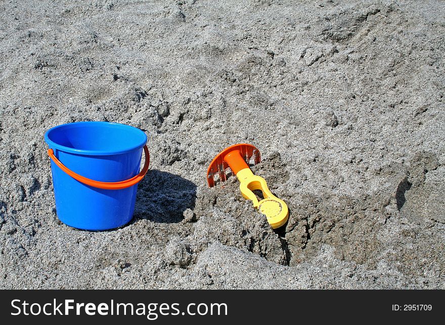 A bucket and rake in the sand at the beach