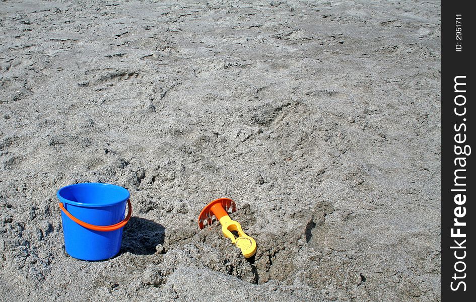 A bucket and rake on a beach. A bucket and rake on a beach
