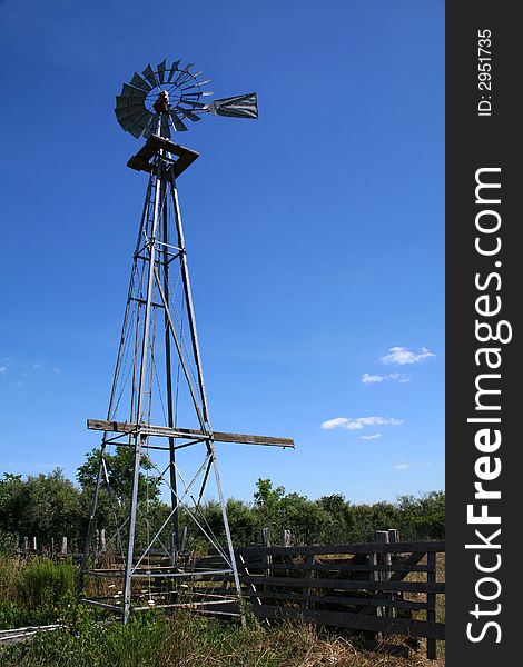 A farm windmill standing tall in the field - energy conservation the old fashioned way. A farm windmill standing tall in the field - energy conservation the old fashioned way