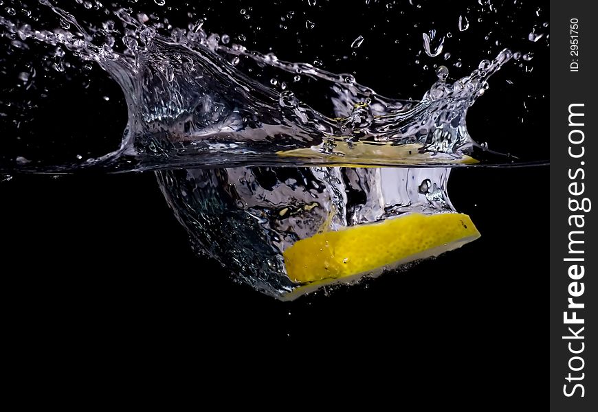 Splashing lemon into the water over black background