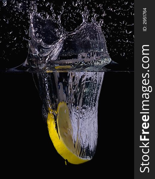 Splashing lemon into the water over black background