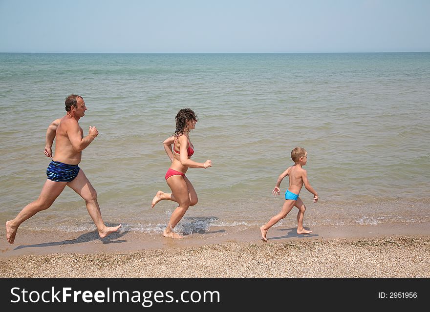 Grandfather with daughter and grandson run as to beach