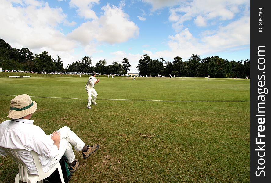 Cricketer about to throw the Ball watched by a seated Spectator. Cricketer about to throw the Ball watched by a seated Spectator