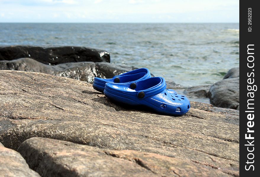 Blue clogs on a cliff by the ocean