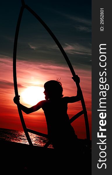 Young boy swinging by the sea at red dusk. Young boy swinging by the sea at red dusk