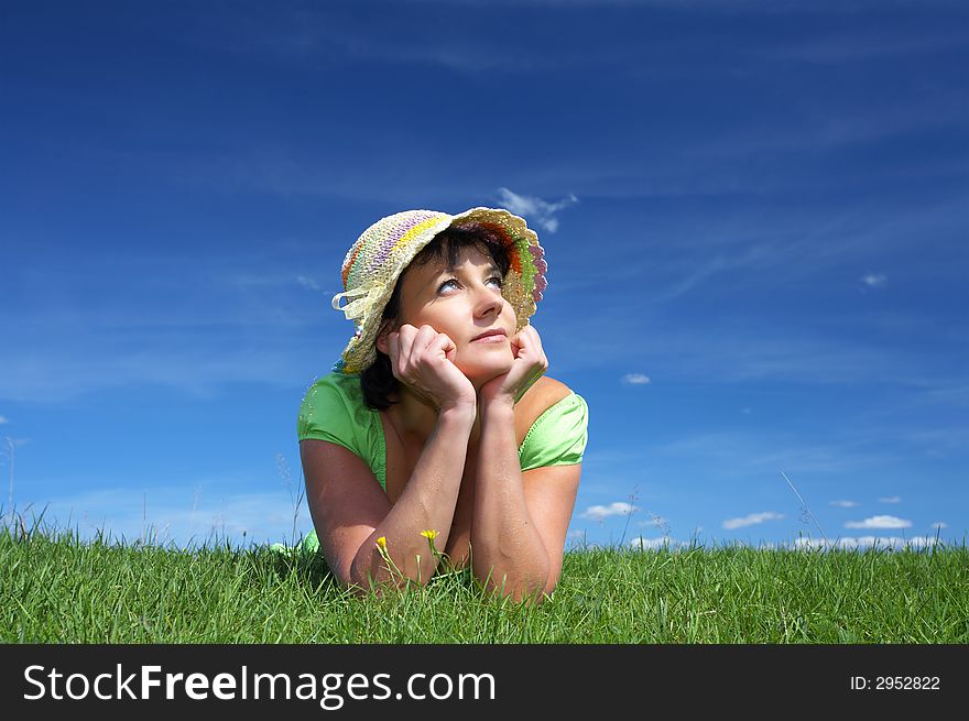 Portrait of young beautiful woman in straw hat laying on green grass. Portrait of young beautiful woman in straw hat laying on green grass