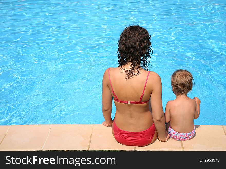 Mother and the daughter sit at pool