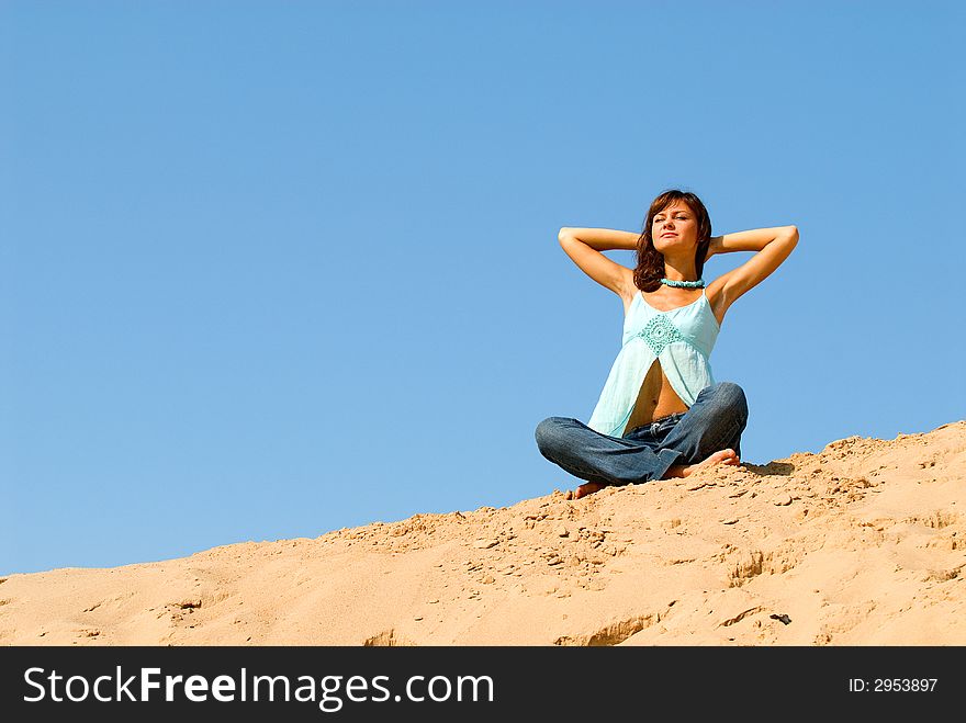 The young woman is engaged in meditation on sand. The young woman is engaged in meditation on sand