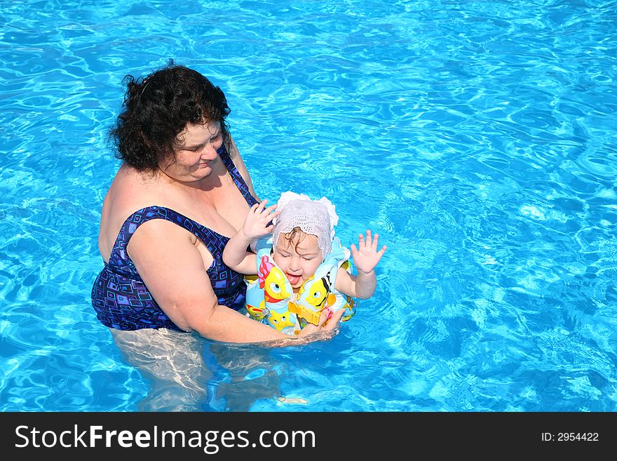 The grandmother plays with the granddaughter in pool. The grandmother plays with the granddaughter in pool