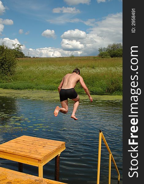 Freezing motion of a boy jumping into the river from a stage. Freezing motion of a boy jumping into the river from a stage