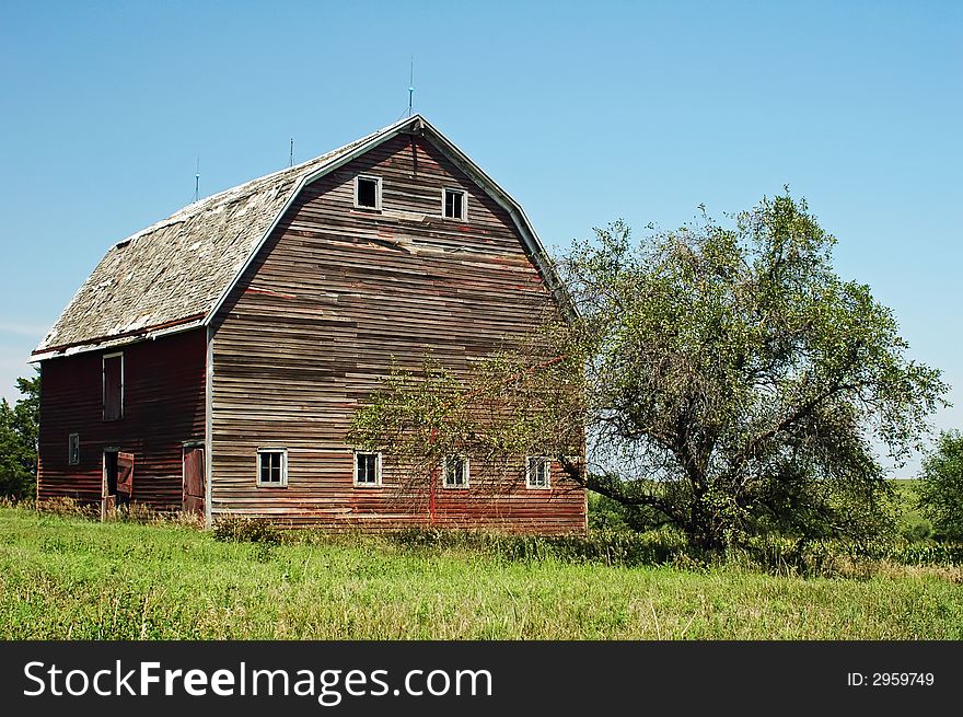 Old red wood barn in field with blue sky. Old red wood barn in field with blue sky.
