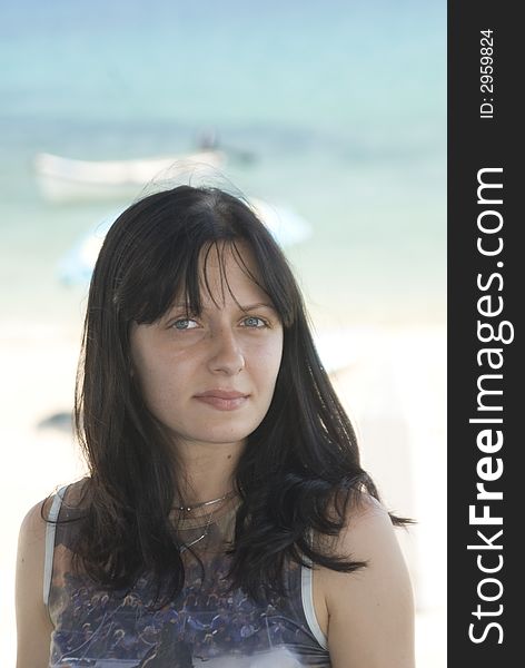 Attractive young woman with slight smile beach and boats in background. Attractive young woman with slight smile beach and boats in background