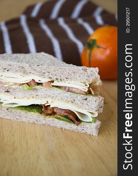 Close up bacon and chicken sandwich on wooden table with tomato background. Close up bacon and chicken sandwich on wooden table with tomato background