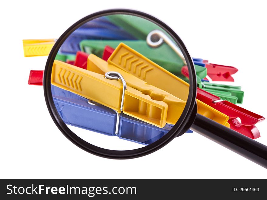 Colorful clothespins through magnifier isolated on white.