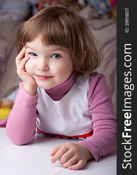 Girl sitting at the table with head resting on arm and looking curious