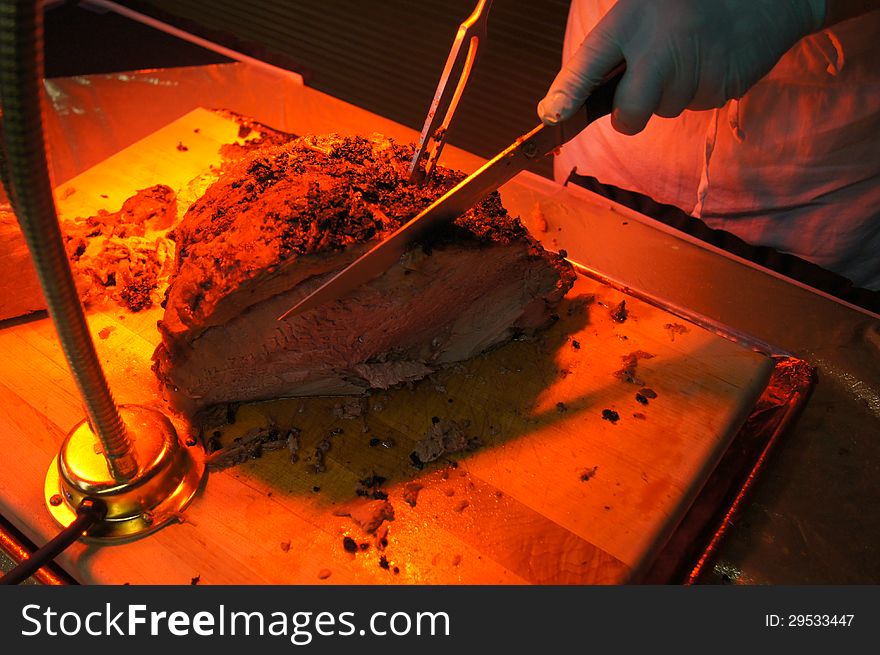 Carving Heated Roast Beef on Cutting Board and under food heat lamp. Carving Heated Roast Beef on Cutting Board and under food heat lamp