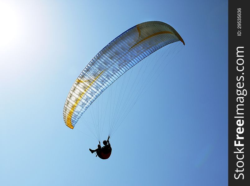 Silhouette of paraglider against the clear blue sky